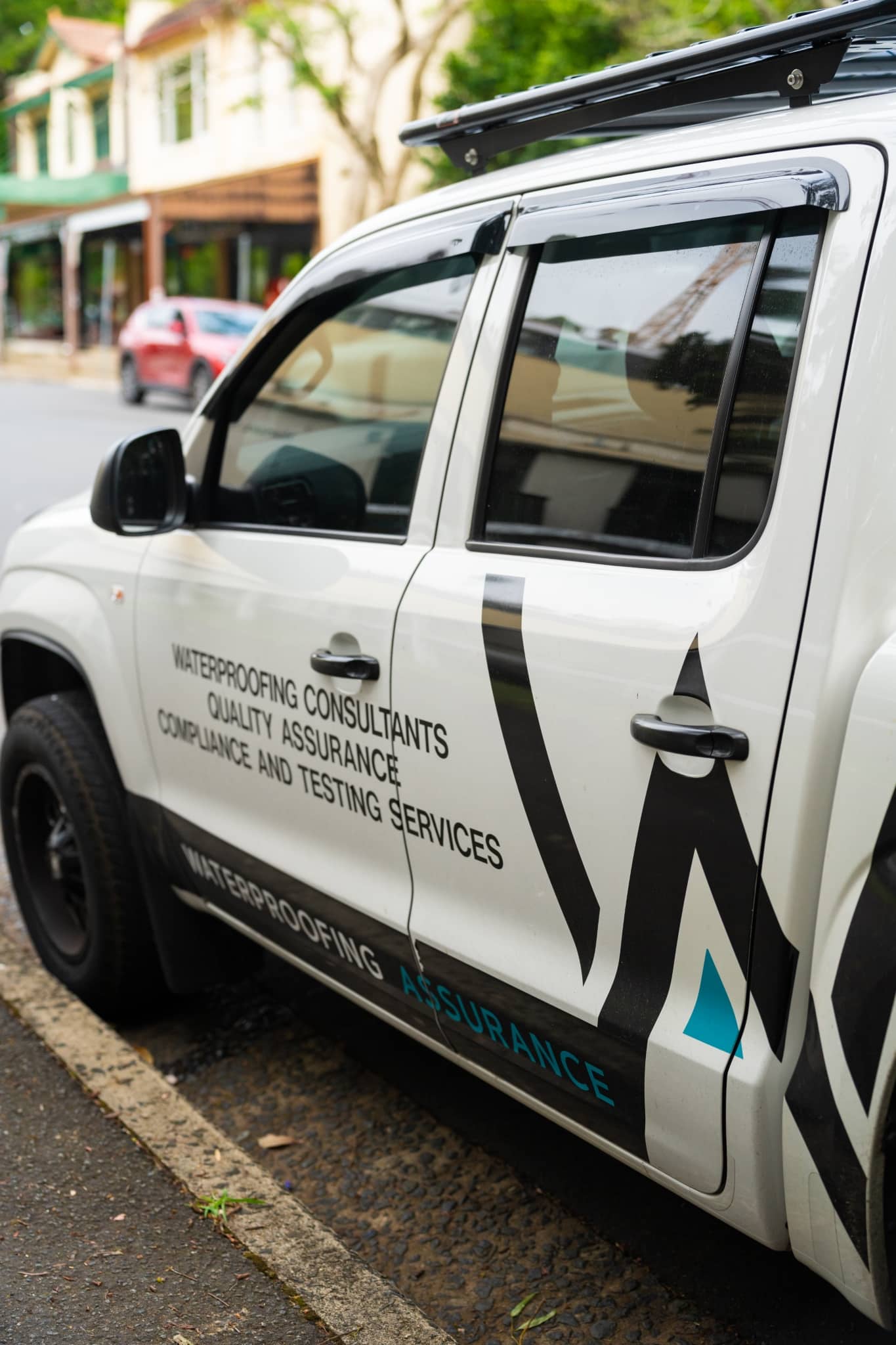 A white truck with waterproofing parked on a street.